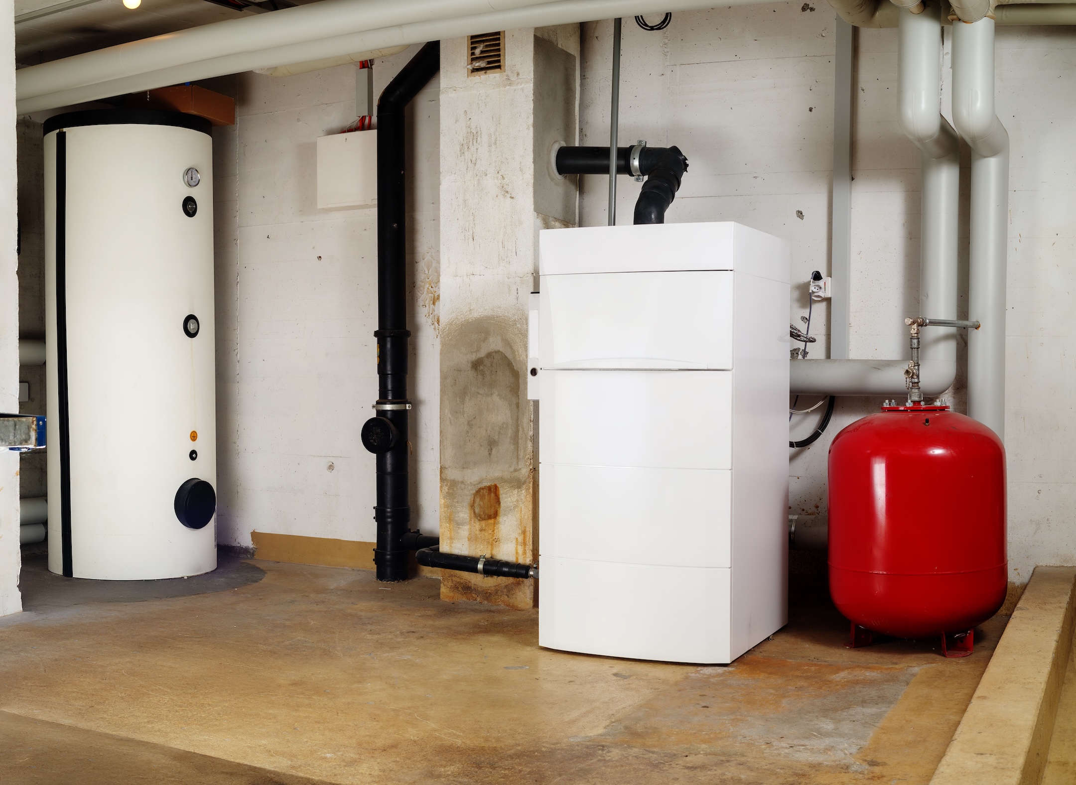 Heating system and hot water tank in residential building. Steel water heater and oil condensing boiler with expansion vessel in boiler room or basement.