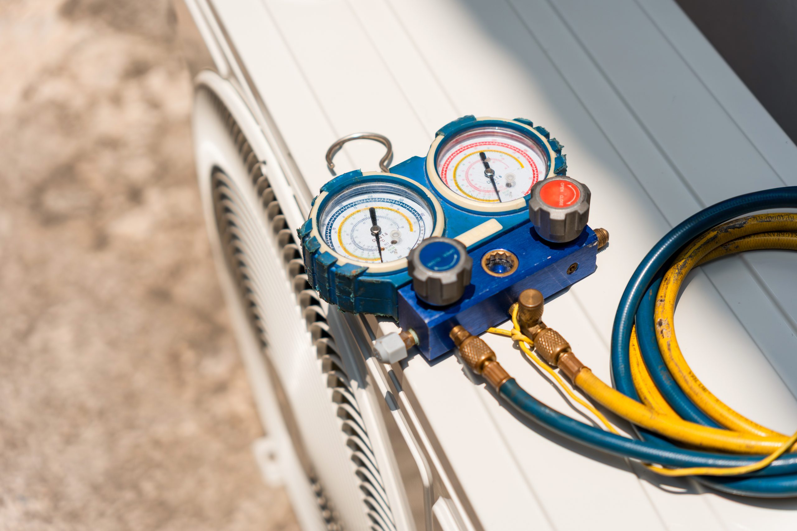 Hvac manifold gauge set on top of outdoor air conditioning unit, refrigerant manifold gauge measuring pressure for ac maintenance, professional hvac tools for air conditioner repair and diagnostics