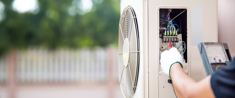 Technician using measuring equipment checking electric at circuit breaker on outdoor air compressor unit after install and check refrigerant air conditioning system maintenance.