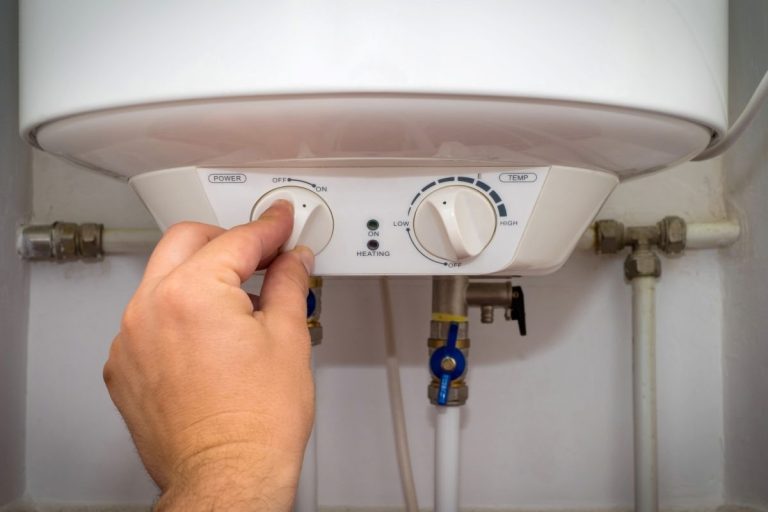 Man-turns-on-the-switch-on-control-panel-of-home-electric-water-heater-